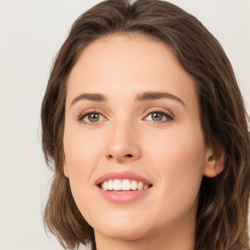 Joyful white young-adult female with long  brown hair and green eyes