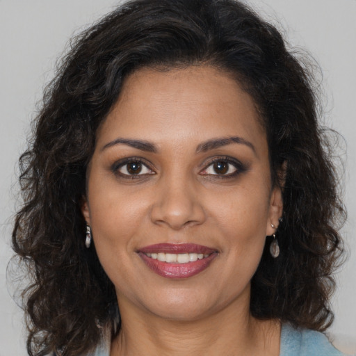 Joyful black young-adult female with long  brown hair and brown eyes