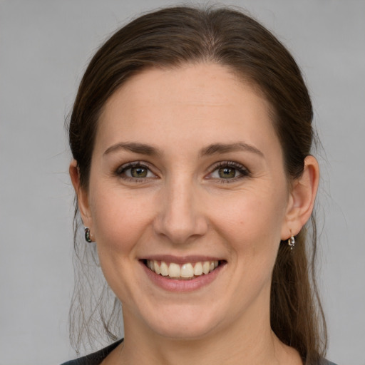 Joyful white young-adult female with medium  brown hair and grey eyes