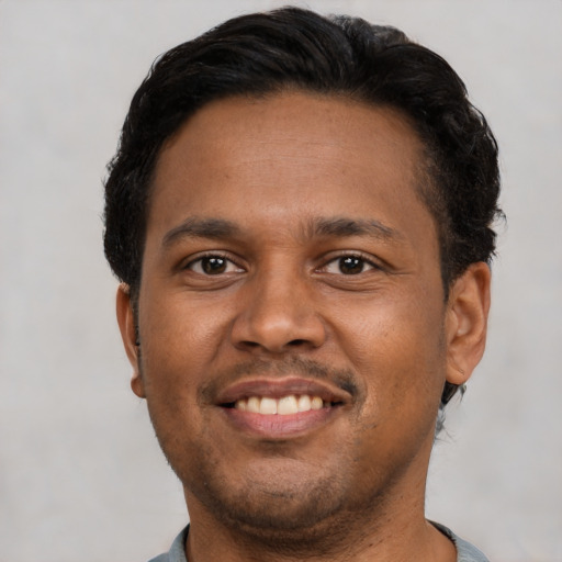 Joyful black young-adult male with short  brown hair and brown eyes