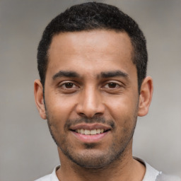 Joyful latino young-adult male with short  black hair and brown eyes