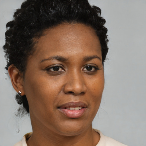 Joyful black young-adult female with short  black hair and brown eyes