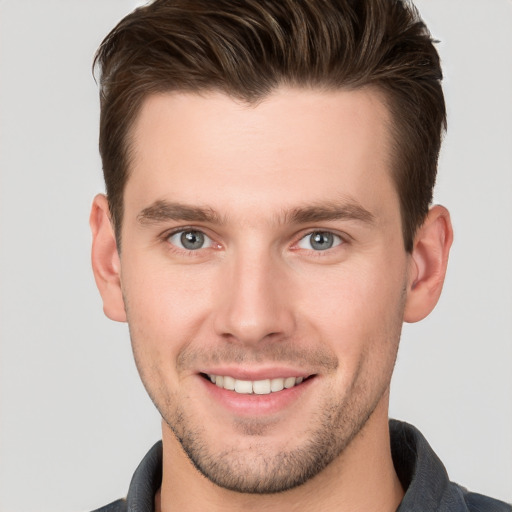 Joyful white young-adult male with short  brown hair and grey eyes