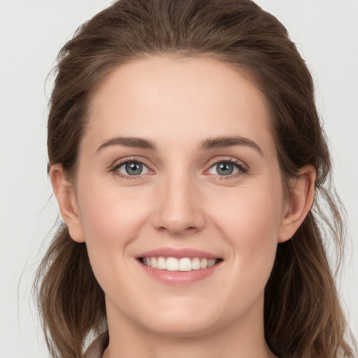 Joyful white young-adult female with long  brown hair and grey eyes