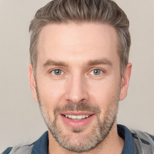 Joyful white adult male with short  brown hair and blue eyes