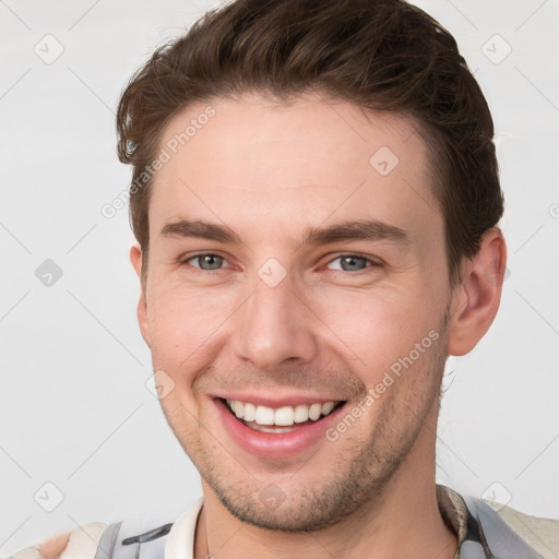 Joyful white young-adult male with short  brown hair and grey eyes