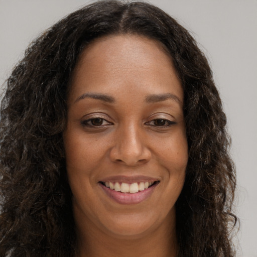 Joyful black young-adult female with long  brown hair and brown eyes
