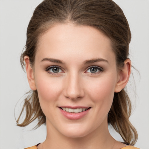 Joyful white young-adult female with medium  brown hair and grey eyes