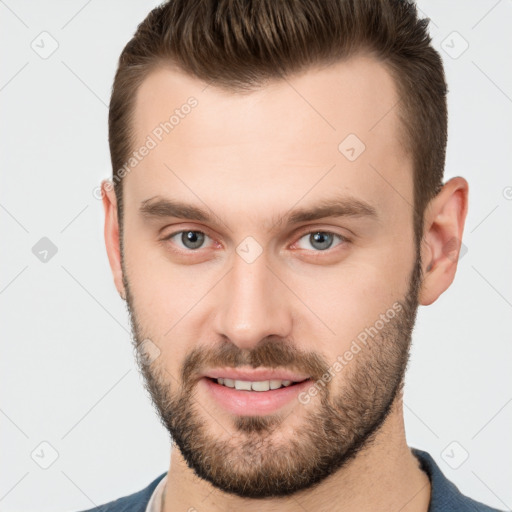 Joyful white young-adult male with short  brown hair and grey eyes