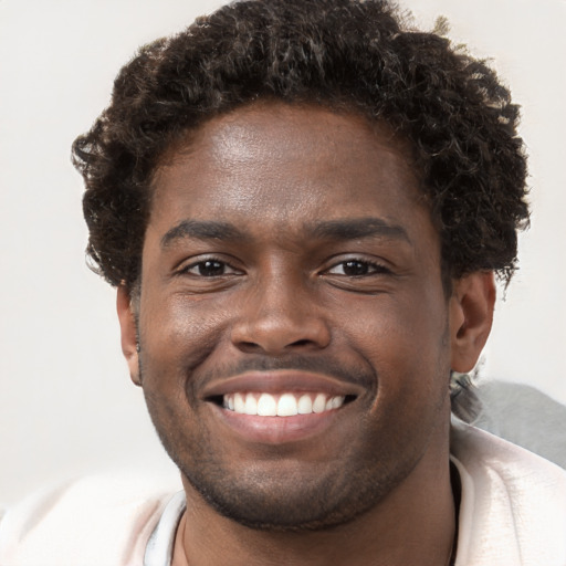 Joyful black young-adult male with short  brown hair and brown eyes