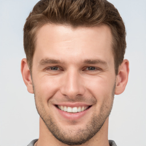 Joyful white young-adult male with short  brown hair and grey eyes