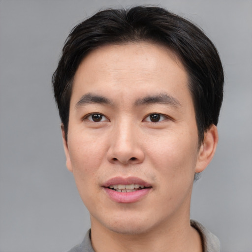 Joyful asian young-adult male with short  brown hair and brown eyes