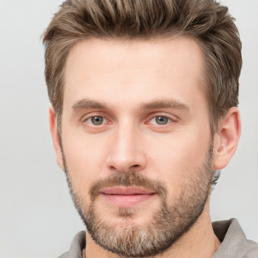 Joyful white young-adult male with short  brown hair and grey eyes