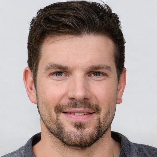 Joyful white young-adult male with short  brown hair and grey eyes