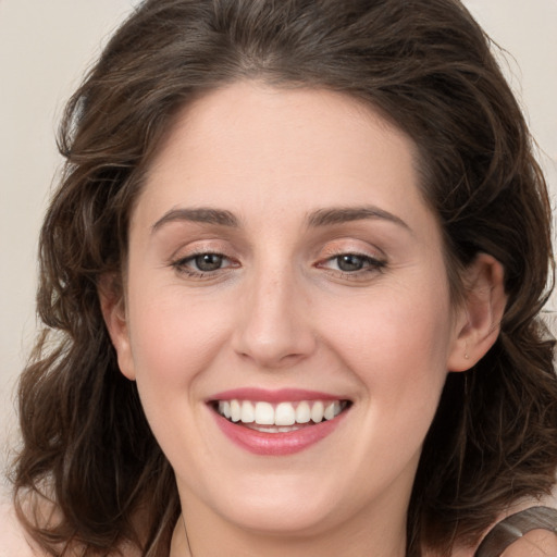 Joyful white young-adult female with medium  brown hair and grey eyes