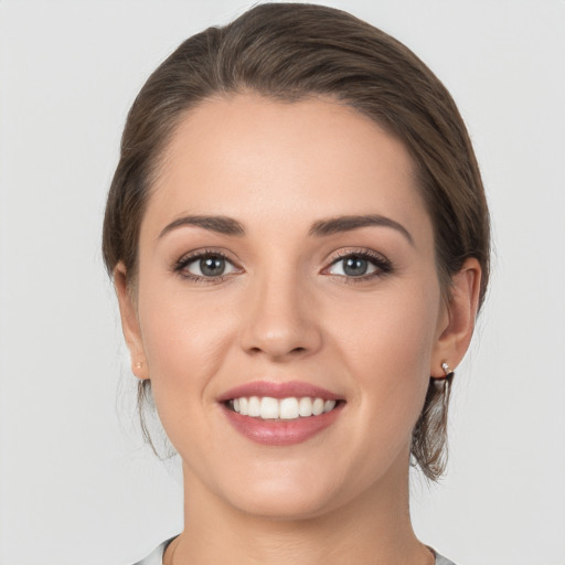 Joyful white young-adult female with medium  brown hair and grey eyes