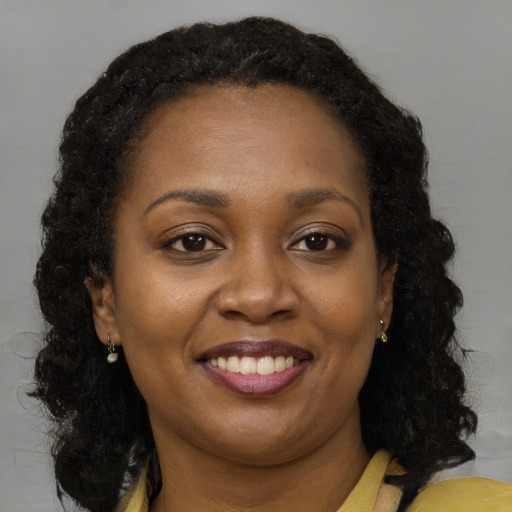 Joyful black young-adult female with long  brown hair and brown eyes