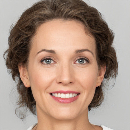 Joyful white young-adult female with medium  brown hair and grey eyes