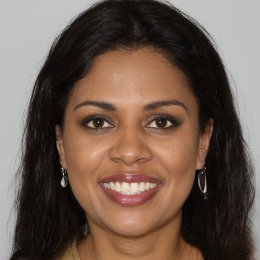 Joyful black young-adult female with long  brown hair and brown eyes