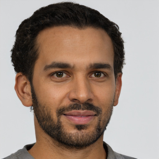 Joyful latino young-adult male with short  black hair and brown eyes