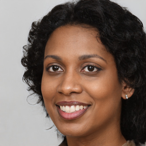Joyful black young-adult female with long  black hair and brown eyes