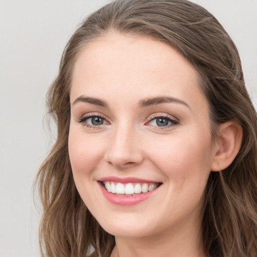 Joyful white young-adult female with long  brown hair and blue eyes