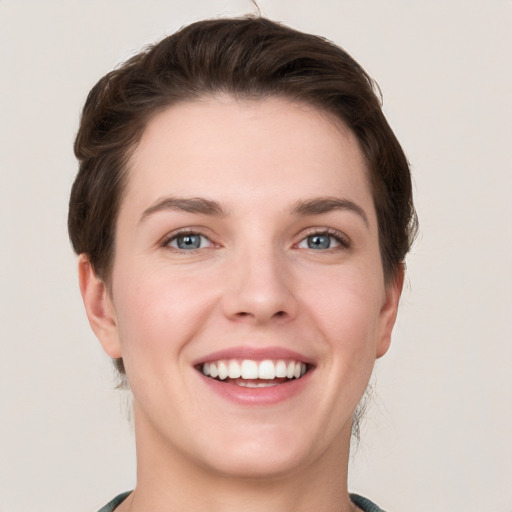 Joyful white young-adult female with short  brown hair and grey eyes