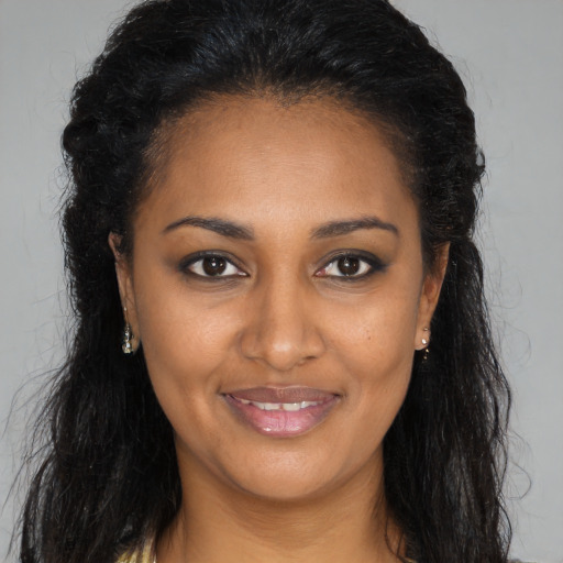 Joyful black young-adult female with long  brown hair and brown eyes