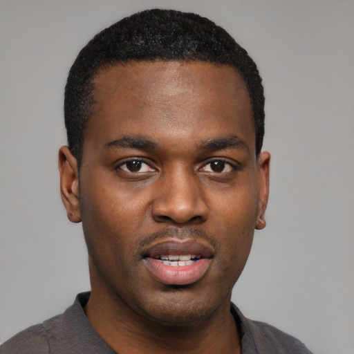 Joyful black young-adult male with short  black hair and brown eyes