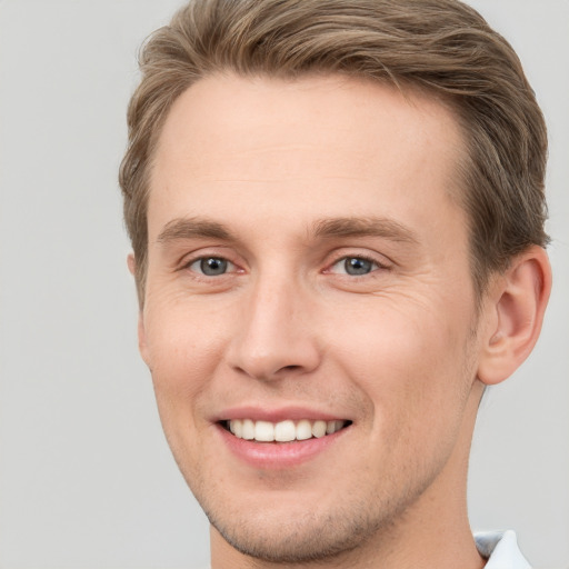 Joyful white young-adult male with short  brown hair and grey eyes