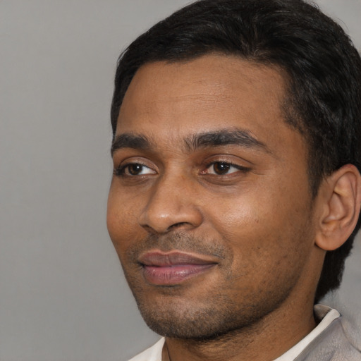 Joyful black young-adult male with short  black hair and brown eyes