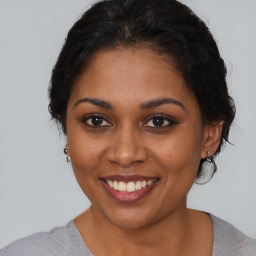 Joyful black young-adult female with medium  brown hair and brown eyes