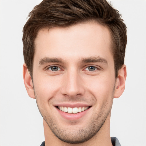 Joyful white young-adult male with short  brown hair and grey eyes