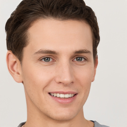 Joyful white young-adult male with short  brown hair and grey eyes