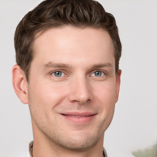 Joyful white young-adult male with short  brown hair and grey eyes