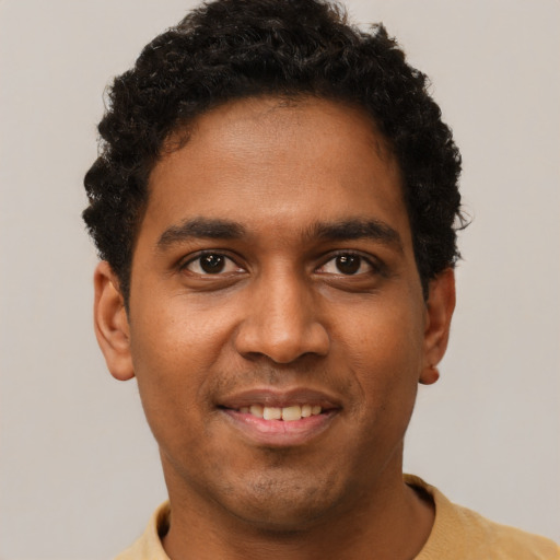 Joyful black young-adult male with short  brown hair and brown eyes
