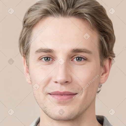 Joyful white young-adult male with short  brown hair and grey eyes