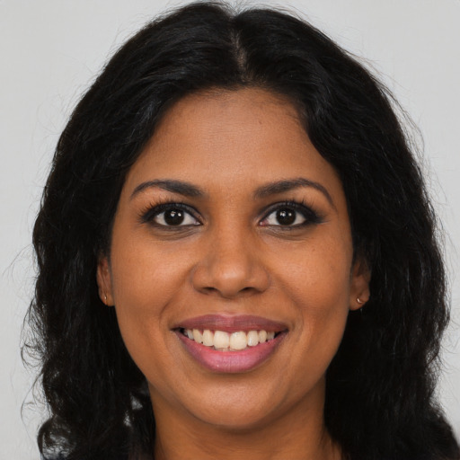 Joyful black young-adult female with long  brown hair and brown eyes