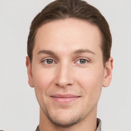 Joyful white young-adult male with short  brown hair and grey eyes