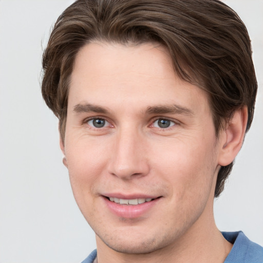 Joyful white young-adult male with short  brown hair and grey eyes