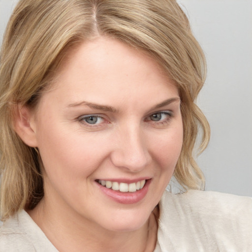 Joyful white young-adult female with medium  blond hair and blue eyes