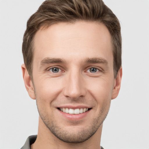 Joyful white young-adult male with short  brown hair and grey eyes