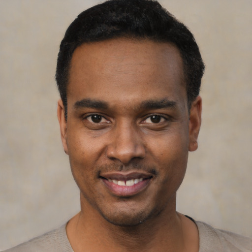 Joyful black young-adult male with short  black hair and brown eyes