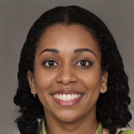 Joyful black young-adult female with long  black hair and brown eyes