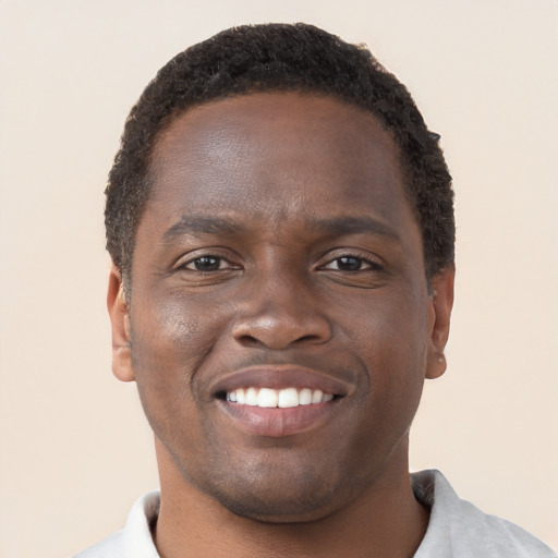 Joyful black young-adult male with short  brown hair and brown eyes