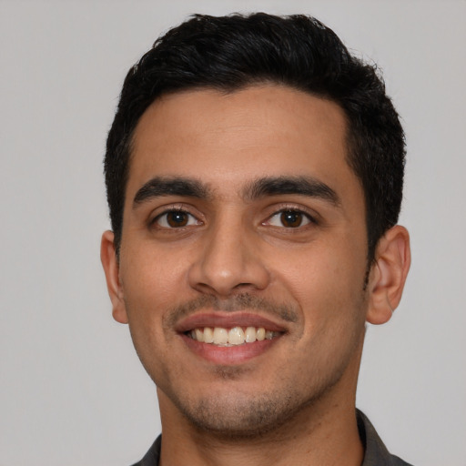 Joyful latino young-adult male with short  black hair and brown eyes