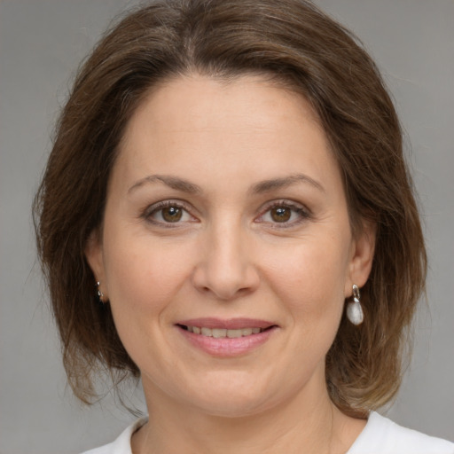 Joyful white adult female with medium  brown hair and green eyes