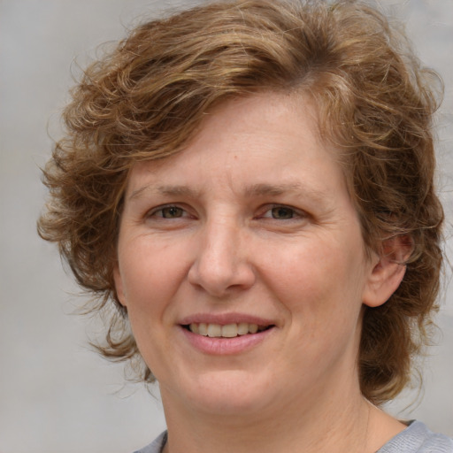 Joyful white adult female with medium  brown hair and blue eyes