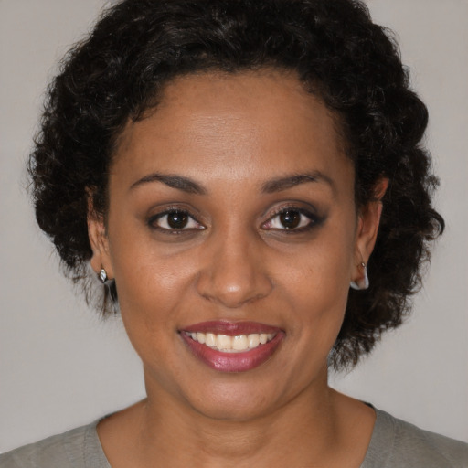 Joyful black young-adult female with short  brown hair and brown eyes