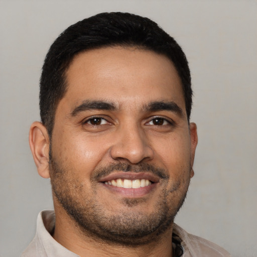 Joyful latino young-adult male with short  black hair and brown eyes